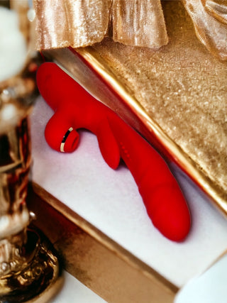 Red suction and thrusting vibrator displayed in gold gift box by INTAKE.