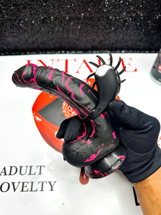 Black vibrating couples ring with tongue teaser on white background. Red and black silicone toy.