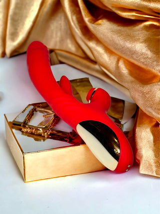 Luxury red clitoral toy with dual tips inside satin gold box.