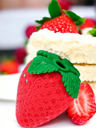 Strawberry Bliss pleasure toy on bed with rose petals and INTAKE pillow