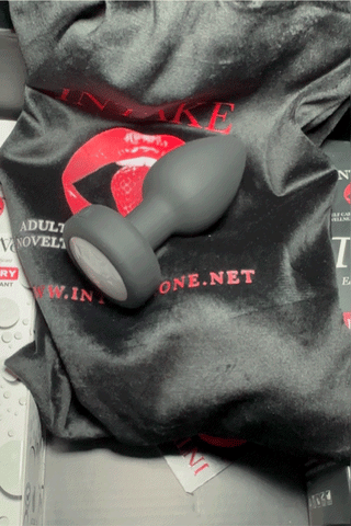 Black vibrating anal plug glowing on colorful surface