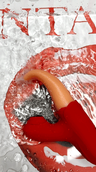 Gloved hand holding red and orange Tongue Action toy with INTAKE lips backdrop.