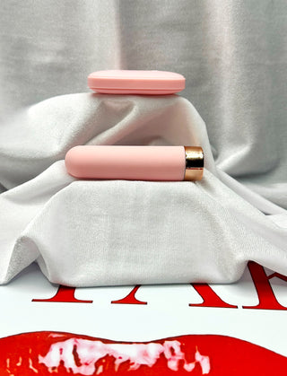 Loaded Pleasure pink bullet vibrator with wireless remote on white satin background.