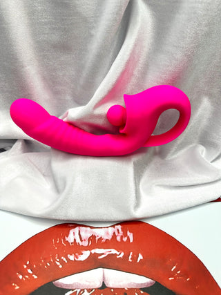 Take Me There pink dual stimulator resting on INTAKE lips backdrop.