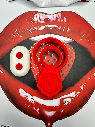 Close-up of red rose-shaped vibrating penis ring and wireless remote on white satin fabric.