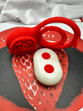 Red silicone dual ring penis vibrator with rose-shaped tip and white remote control INTAKE backdrop.