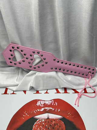 Pink PU leather paddle photographed on white background highlighting heart accents.