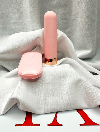 Side view of Loaded Pleasure pink vibrator with gold base beside matching remote.