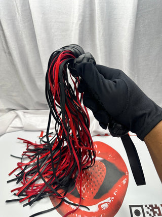 Black and red PU leather whip with braided handle and multiple flogger strands for impact play