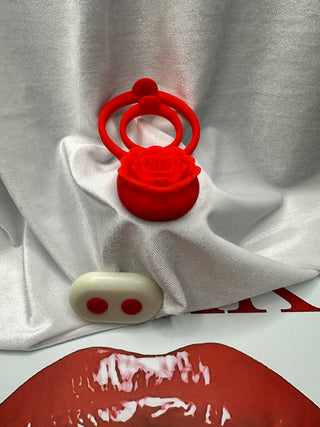 Rose Grip penis ring dual stretch design and remote resting on red lips and strawberry background.