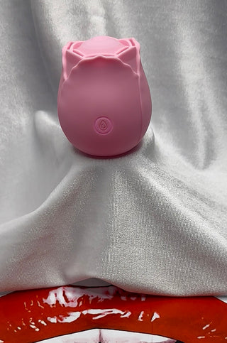 The Ultimate Rose Pink Throb vibrator resting on white silk background.